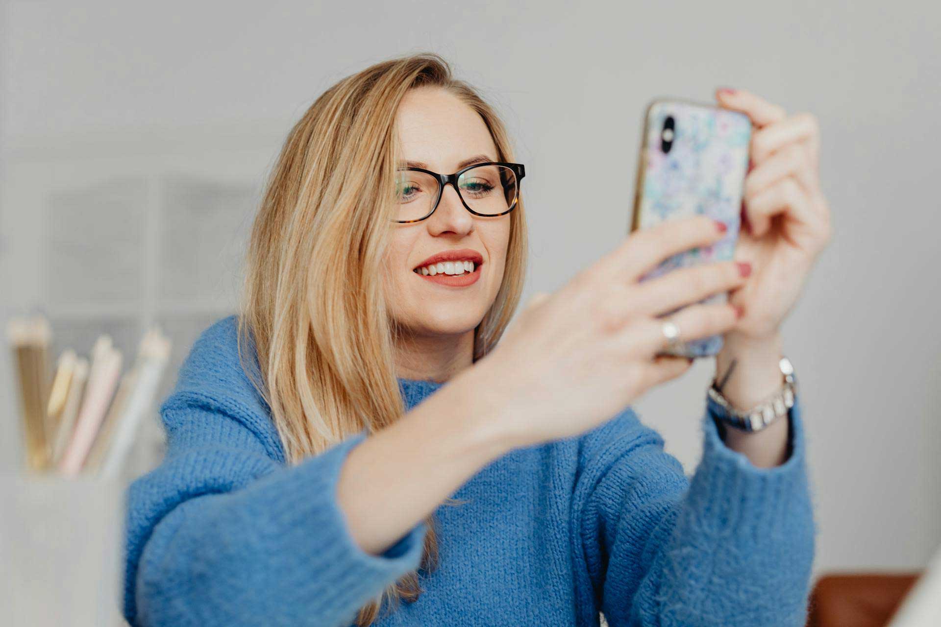 Mulher de óculos assistindo vídeo no smartphone.