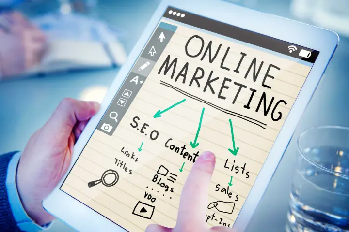 Mão segurando um tablet exibindo um diagrama de estratégias de marketing online, incluindo SEO, conteúdo, listas, vendas e links.
