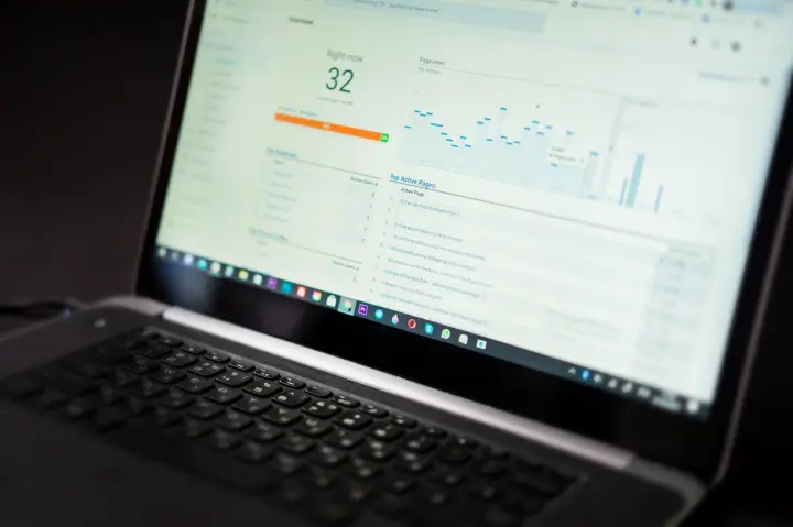 Tela de laptop exibindo dados analíticos do site, incluindo contagem de usuários ativos e páginas com melhor desempenho.