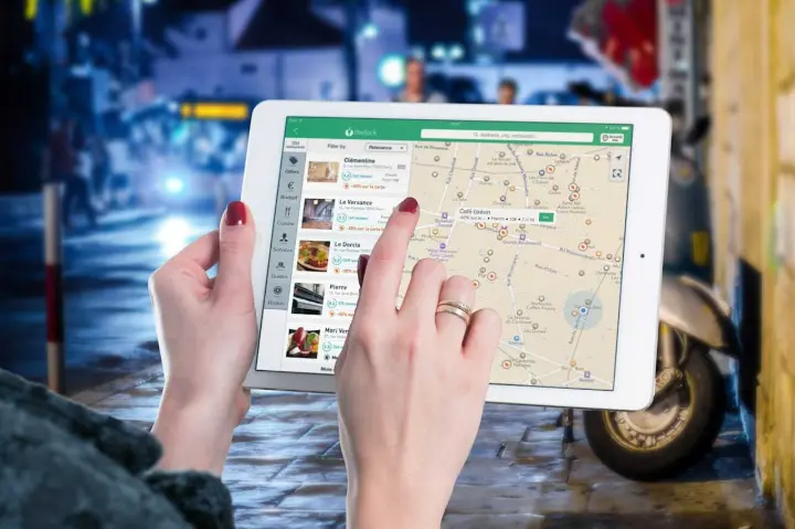 Pessoa usando um tablet para visualizar um mapa e uma lista de restaurantes locais.